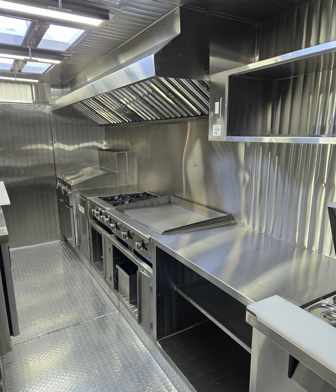 Cocina de acero inoxidable con estufa, plancha, freidora y campana instalada por Flacos